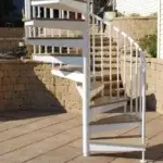 a white powdercoated spiral staircase to patio with pavers and composite decking treads