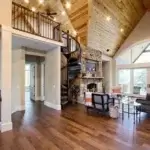 forged iron spiral staircase with solid wood handrail and treads leading to a loft in living room of timberframe mountain house